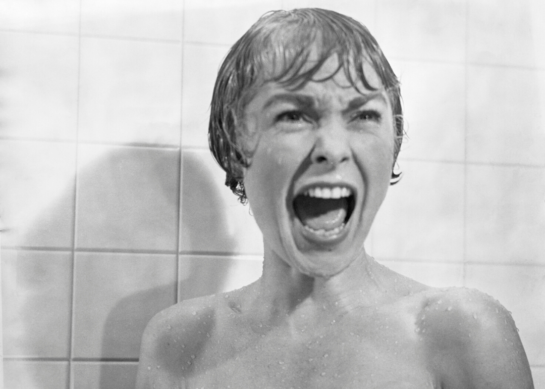 A short haired woman screams in the shower.