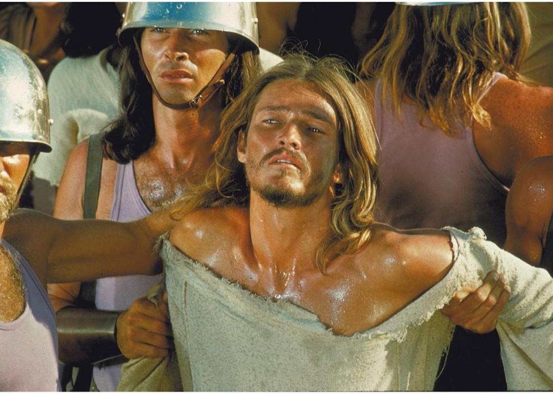 A man dressed as Jesus being held up by other men.