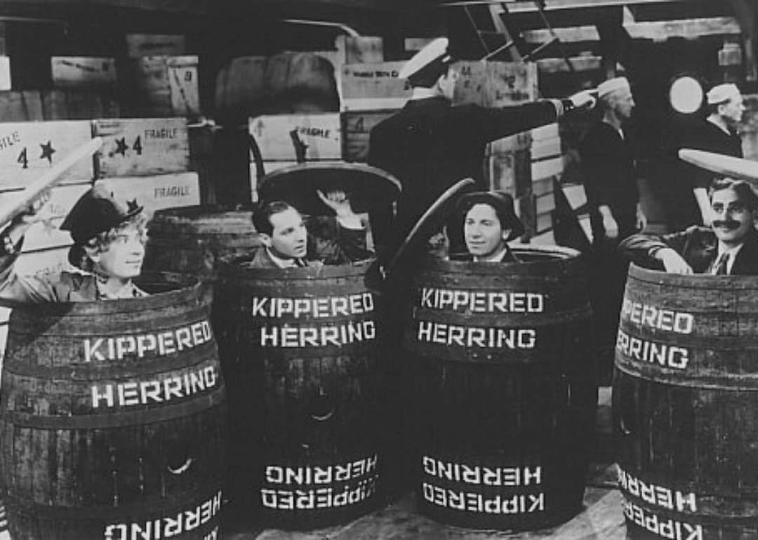 Groucho Marx, Chico Marx, Harpo Marx, and Zeppo Marx popping their heads out of whiskey barrels.