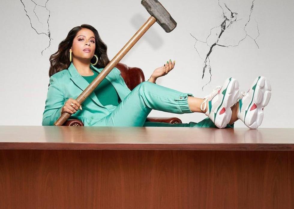 A woman in a track suit sits at a desk with a large gavel.