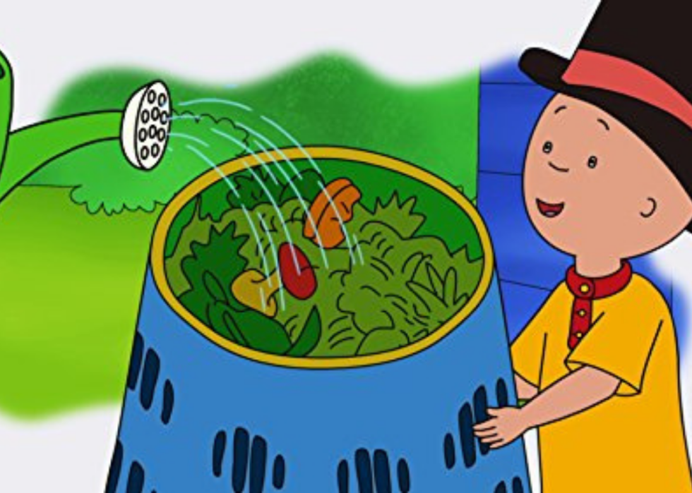 A little boy in a top hat holds a bowl of salad being watered with a watering can.