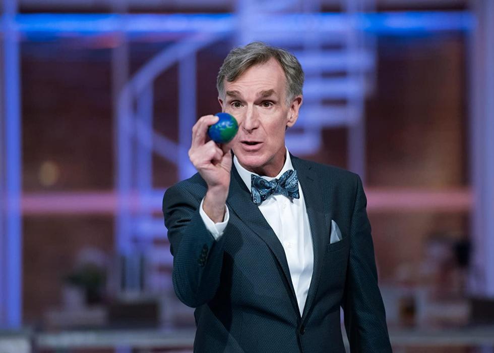 Bill Nye holds a tiny model of earth.