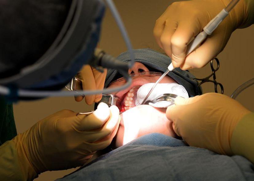 An oral surgeon works on a patient.