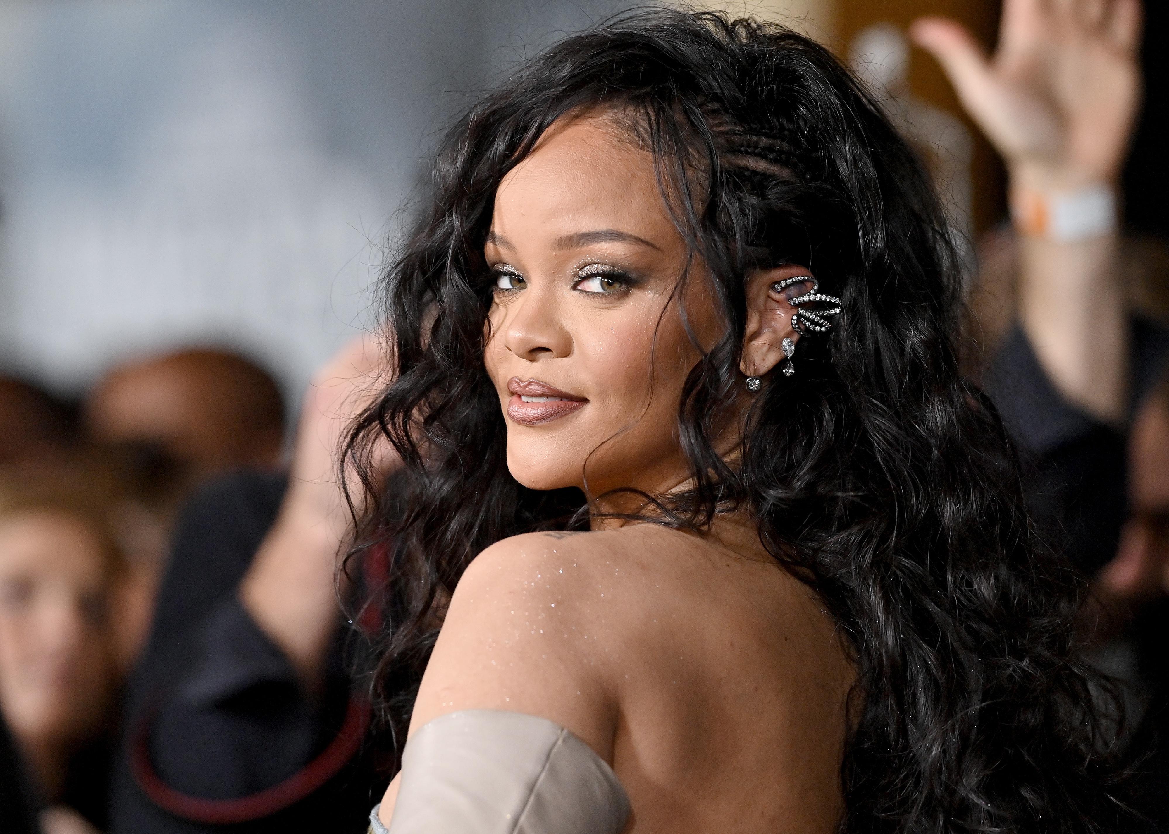 Rihanna looking back over her shoulder with sparkling black hoops in her ears.
