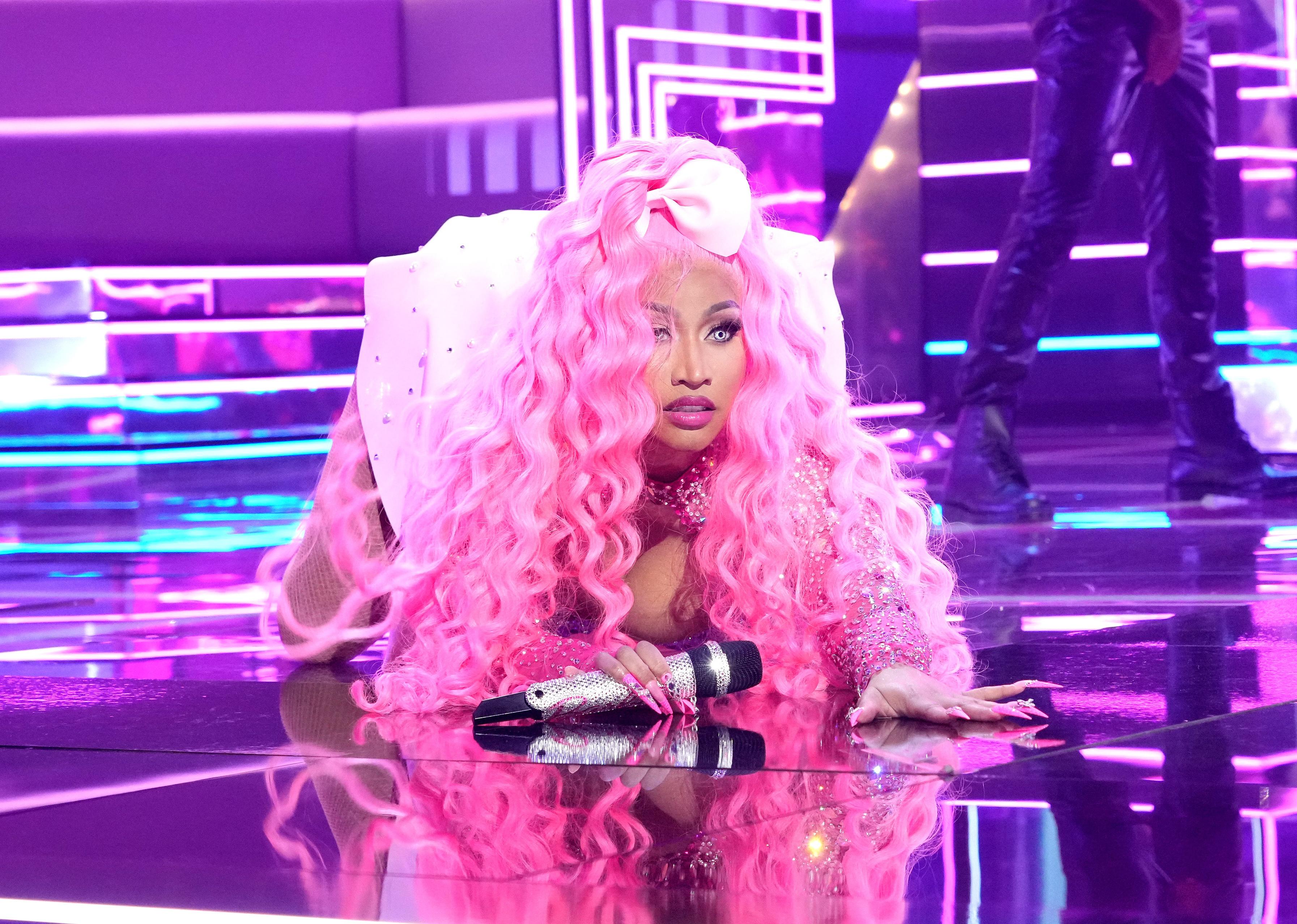 Nicki Minaj in all pink from head to toe on the floor of the stage.