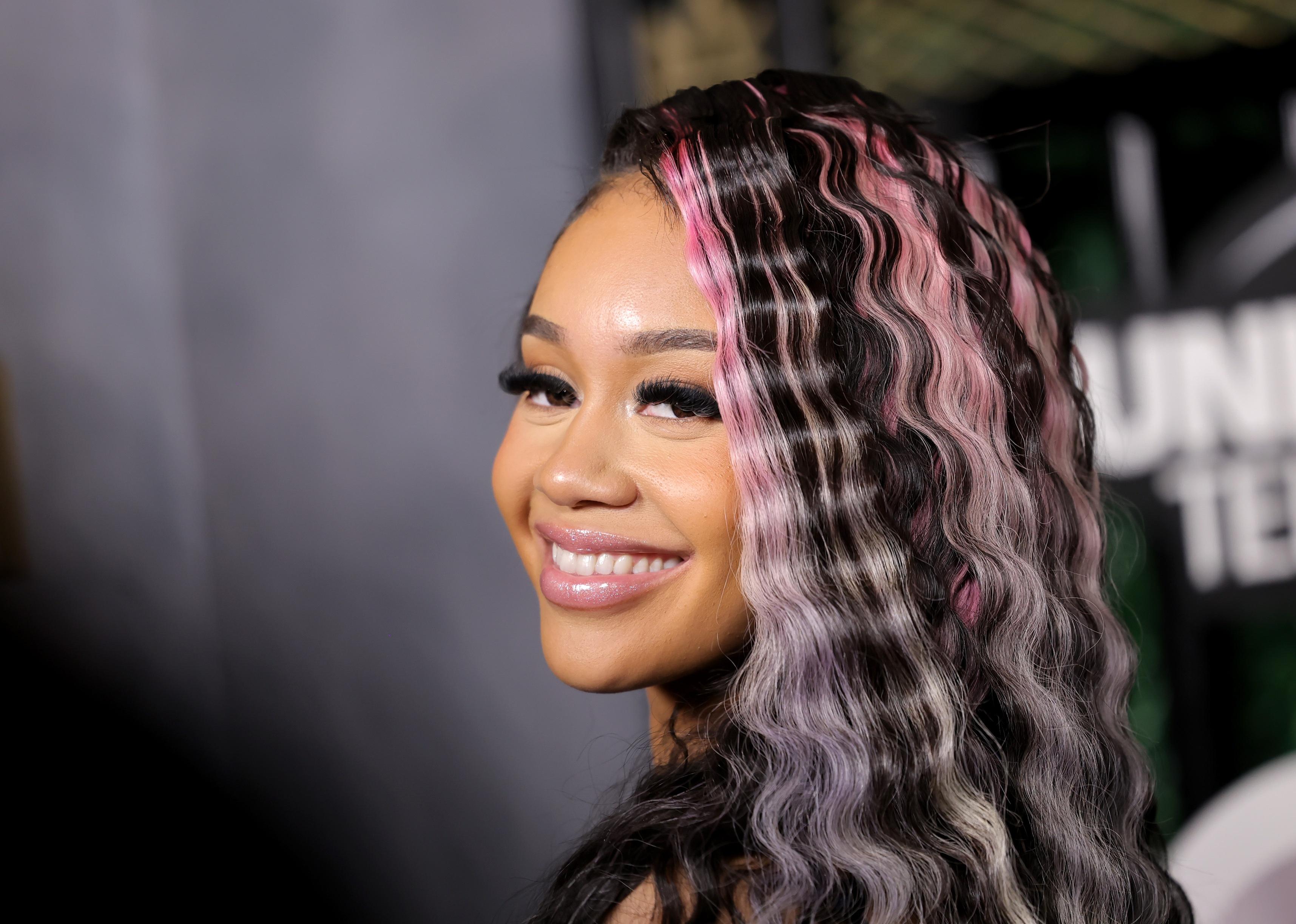 Saweetie posing for a picture with pink highlights in her hair.