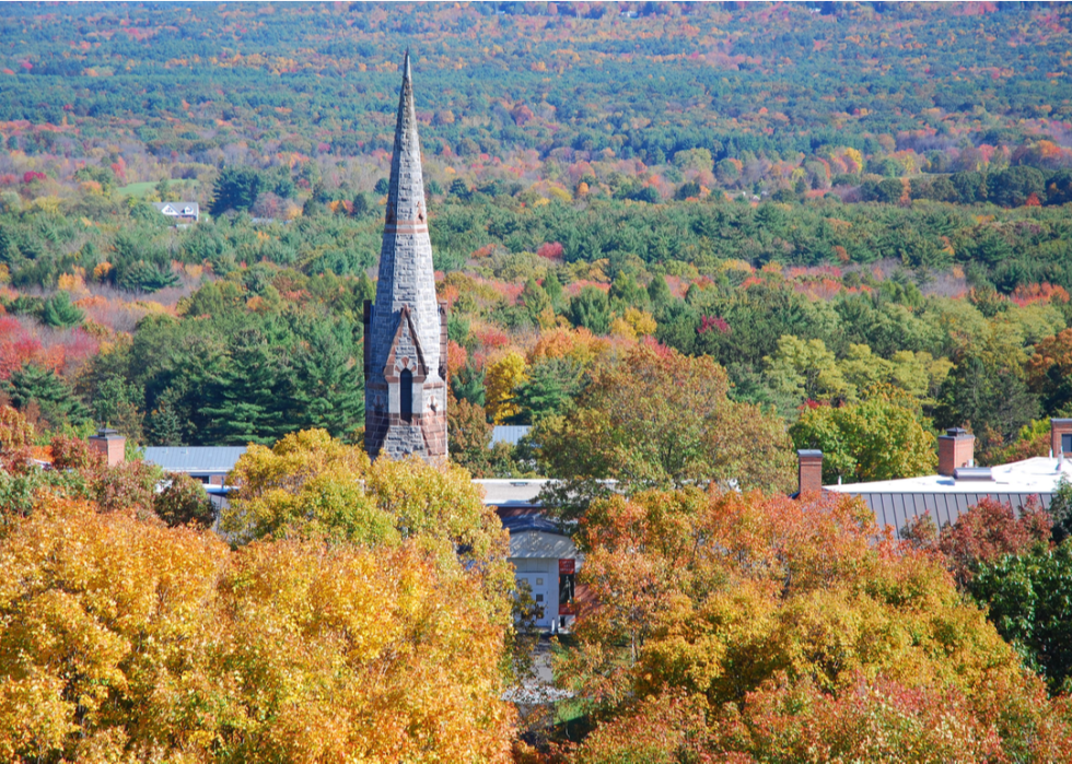 A spire from Amherst College rises above fall foliage.