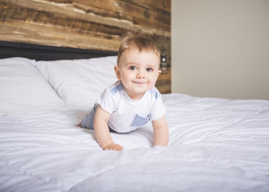 Smiling baby on white bedding.