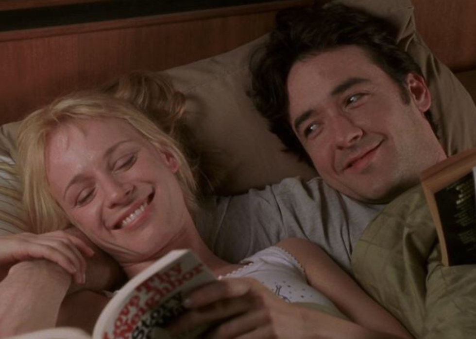 A couple laughs in bed together.