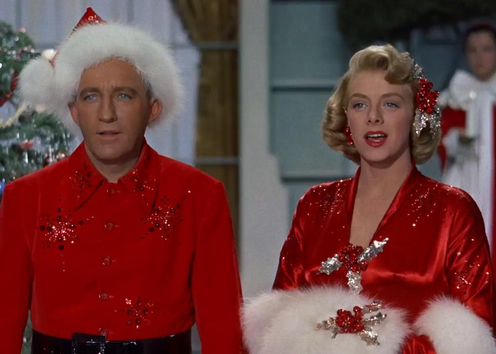 A man and woman are dressed in all red christmas outfits.