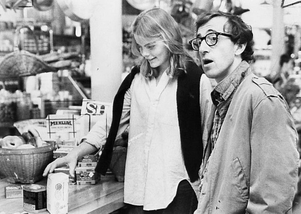 Black and white image of a young man and woman talking at a register.