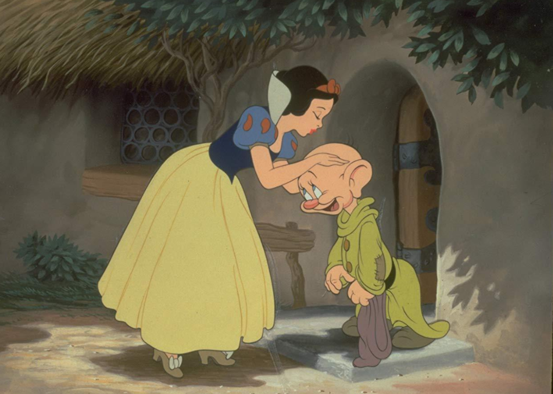 A cartoon of Snow White leaning down to kiss one of the dwarfs.