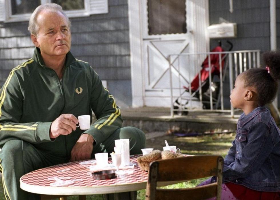 Bill Murray sits at a little girl's table having tea with her.