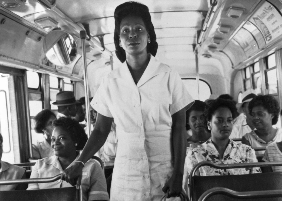 Whoopi Goldberg stands on a bus with other Black passengers.