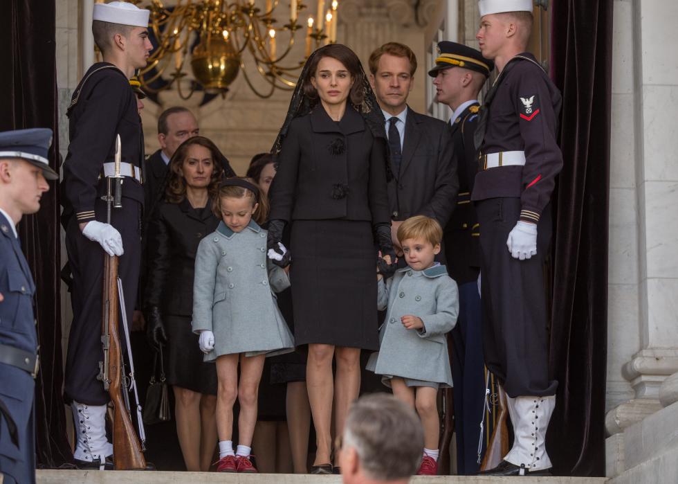 Natalie Portman stands in a doorway as Jackie Kennedy with her children.