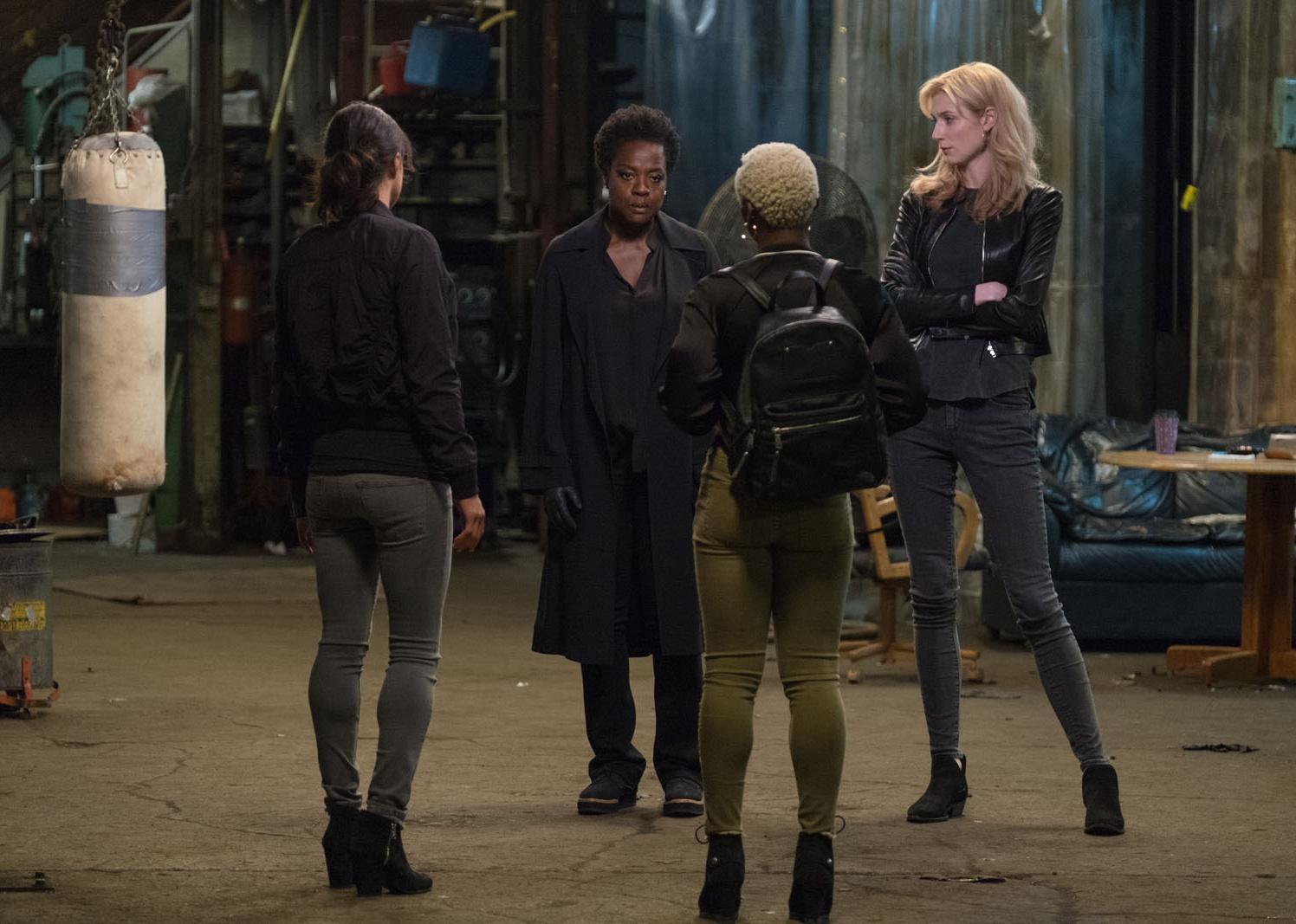 Viola Davis, Michelle Rodriguez, Elizabeth Debicki, and Cynthia Erivo all dressed in dark colors standing in a warehouse.