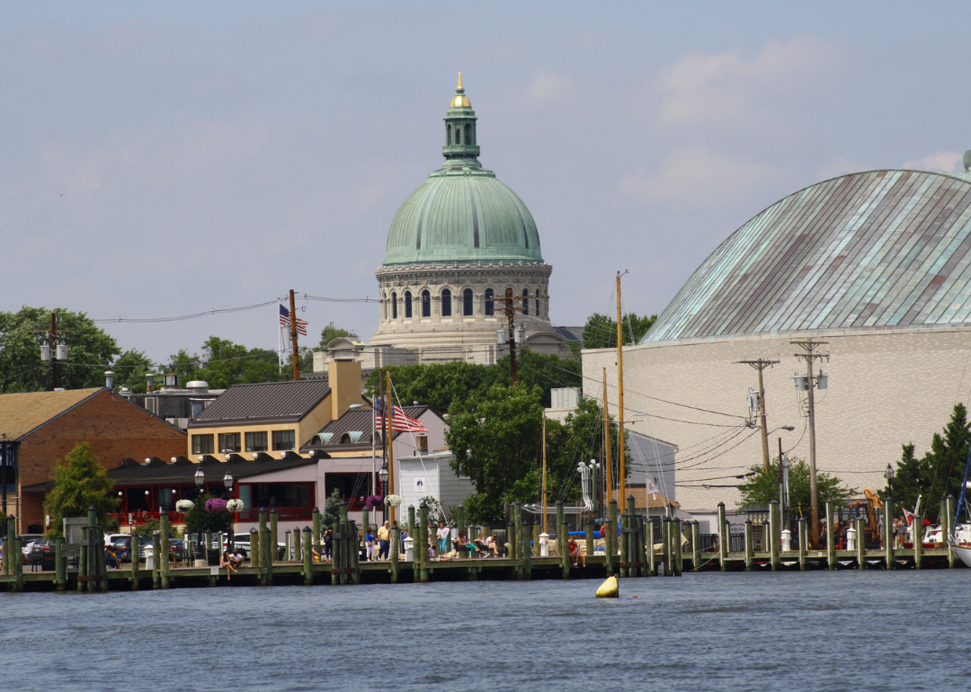 A historic building with a green dome and businesses on the water at the Naval Academy in Annapolis.