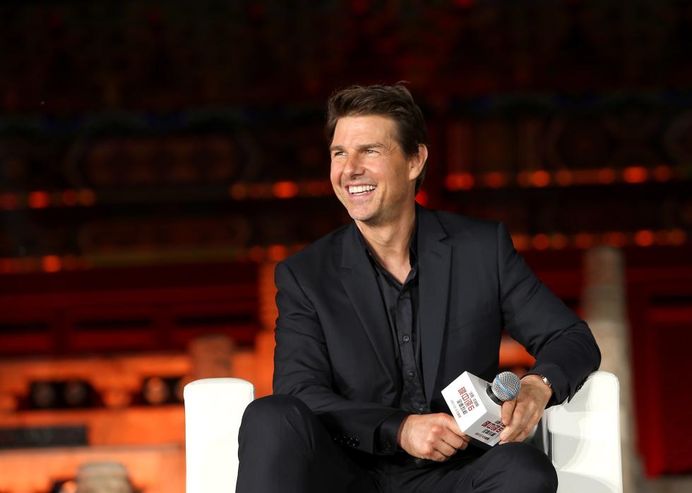 Tom Cruise holding a microphone at a press conference.
