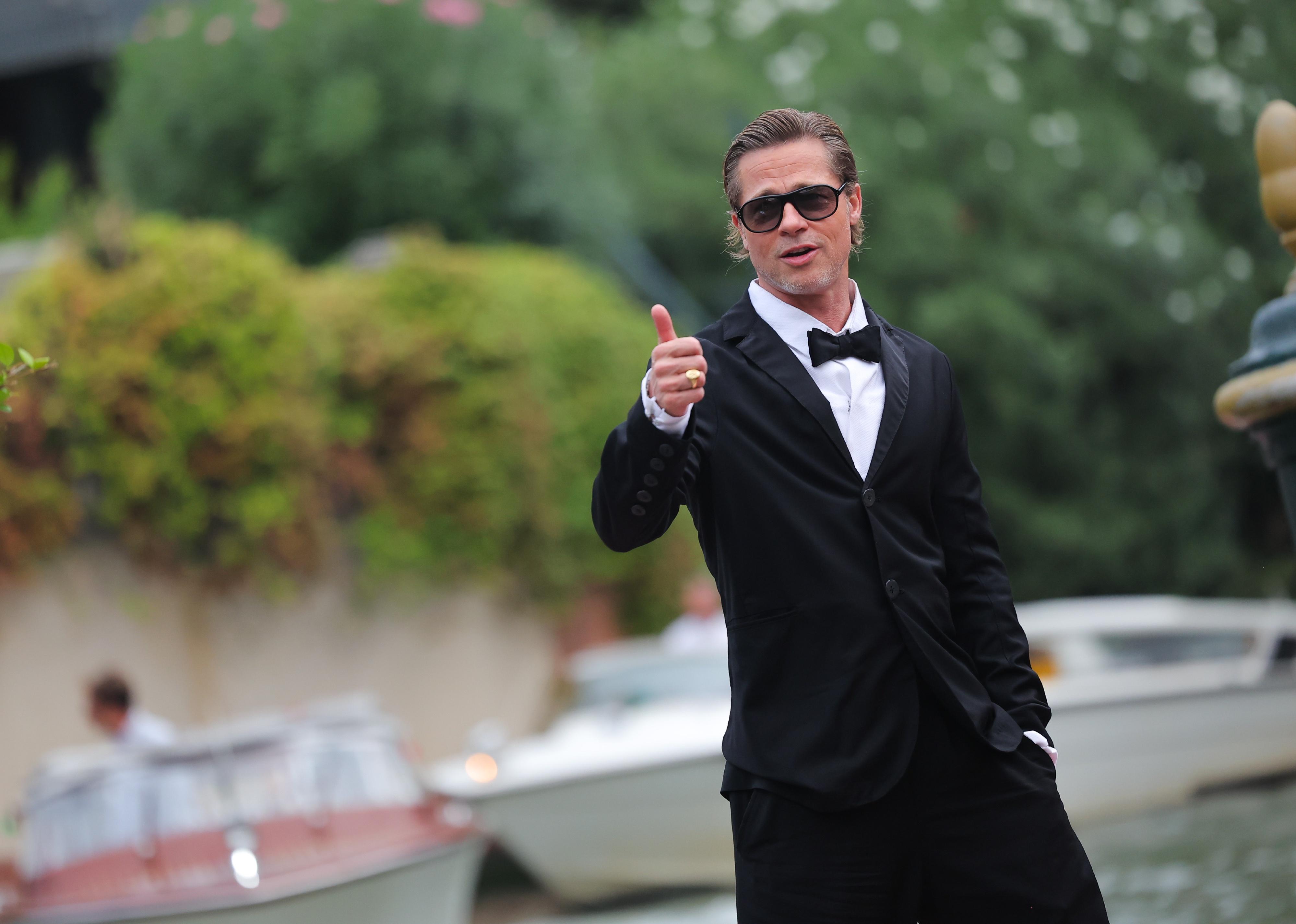 Brad Pitt in a black suit and bowtie giving the thumbs up.