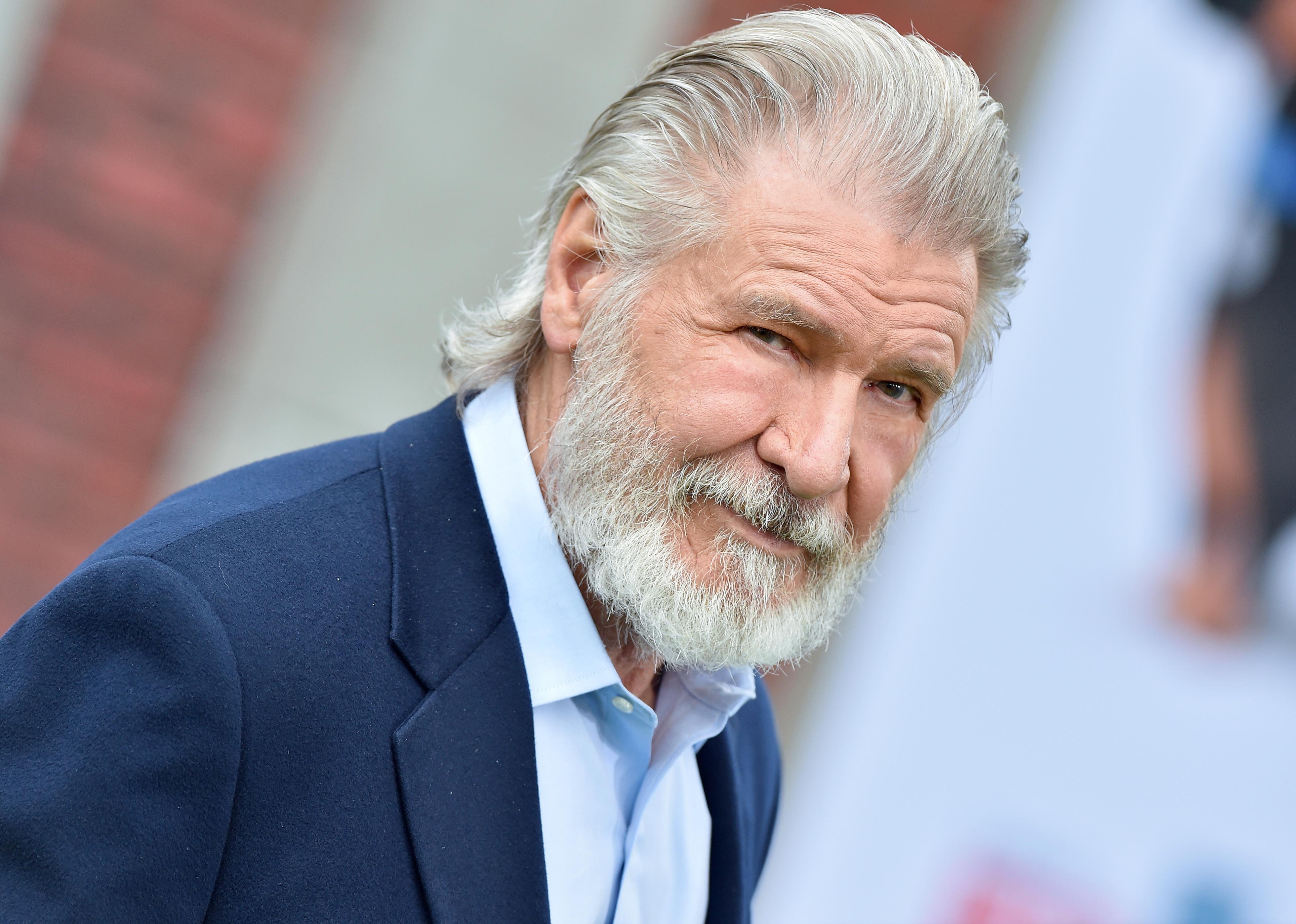 Harrison Ford in a navy suit with a full beard.