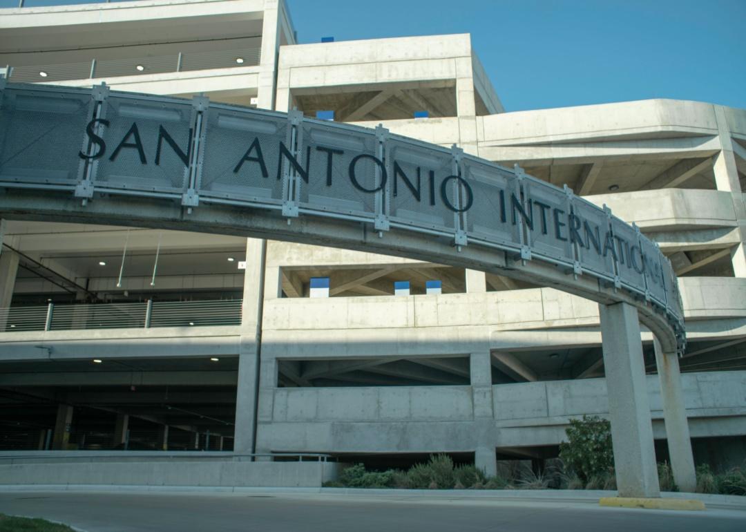 San Antonio International Airport sign in front of a concrete parking garage.