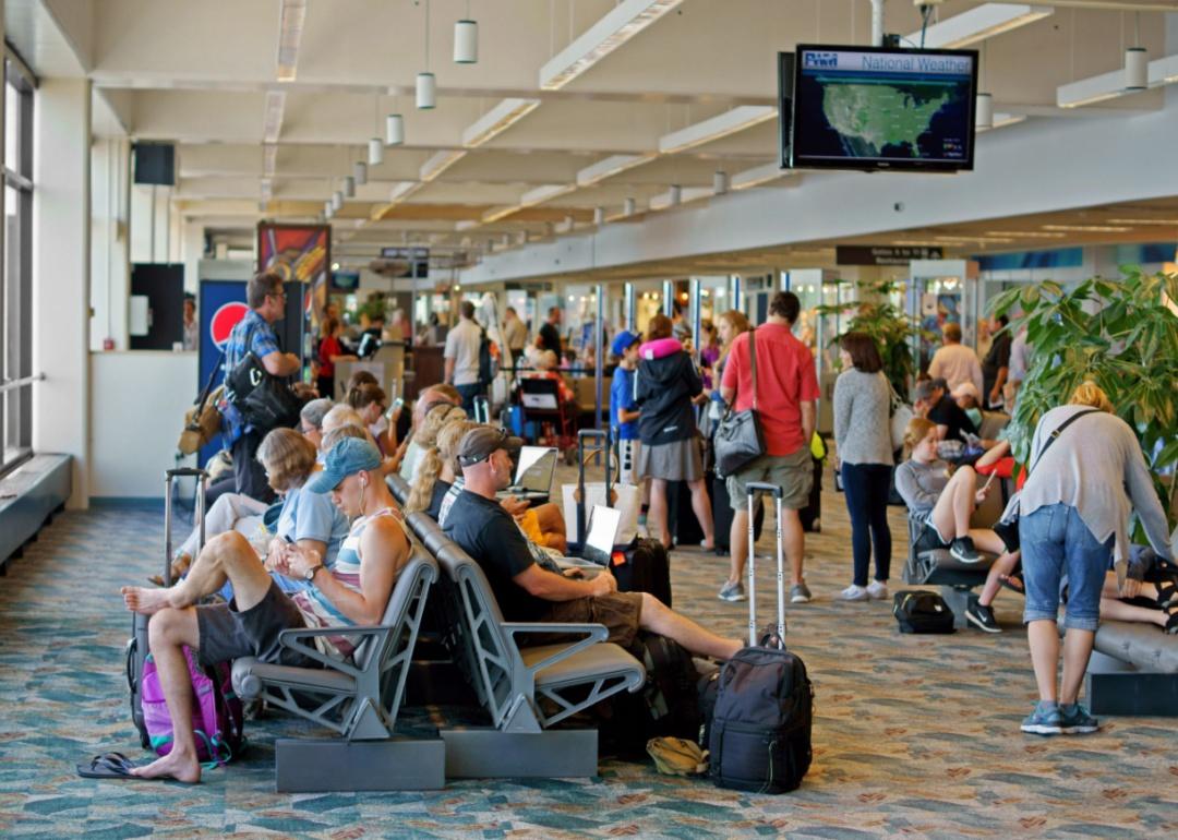 People seated at a gate and waiting in line for flights.