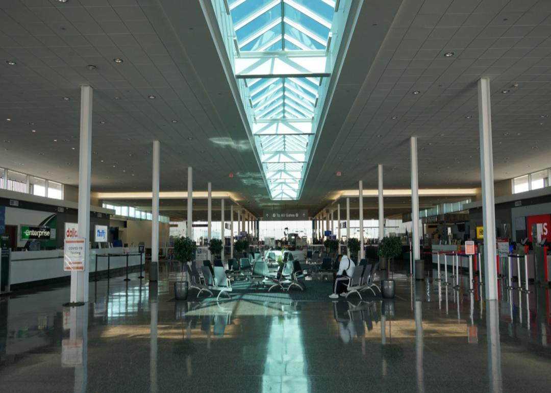 The interior of the Tulsa International airport near rental kiosks with a long skylight in the ceiling.