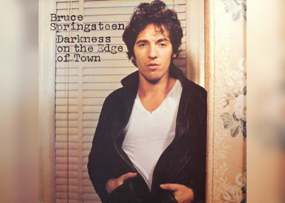 Bruce Springsteen standing in front of blinds and floral wallpaper.