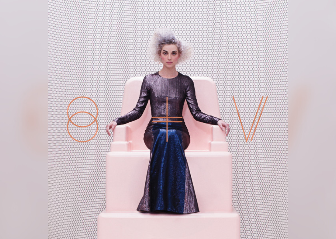 St. Vincent sitting on a pink throne, wearing a shiny dark long dress, with a light pink honeycomb background.