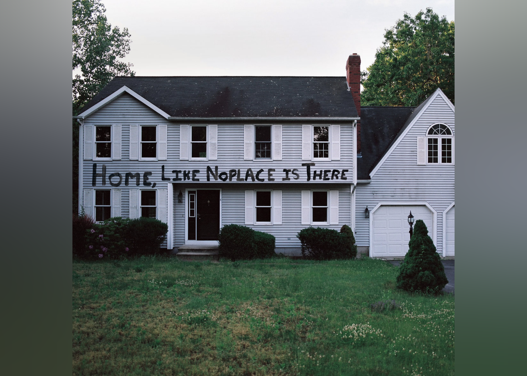 A white and grey home with the album name written across the front of the house.
