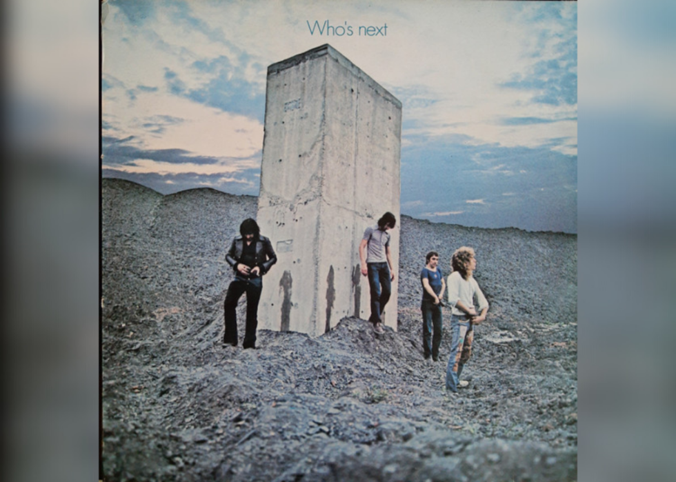 The Who standing in front of a large rectangular stone.