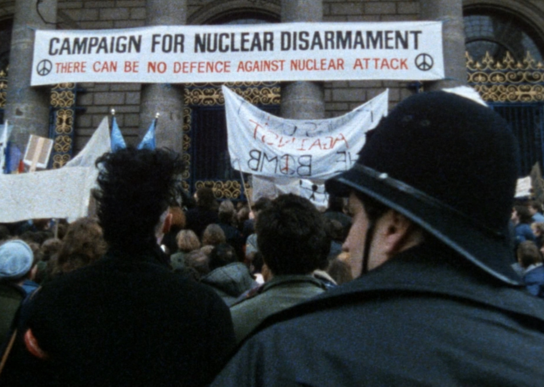 A group of protesters in front of a government building with signs against nuclear war.
