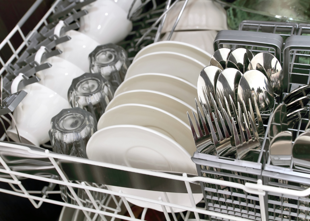Neatly stacked cups, plates and silverware in a dishwasher.