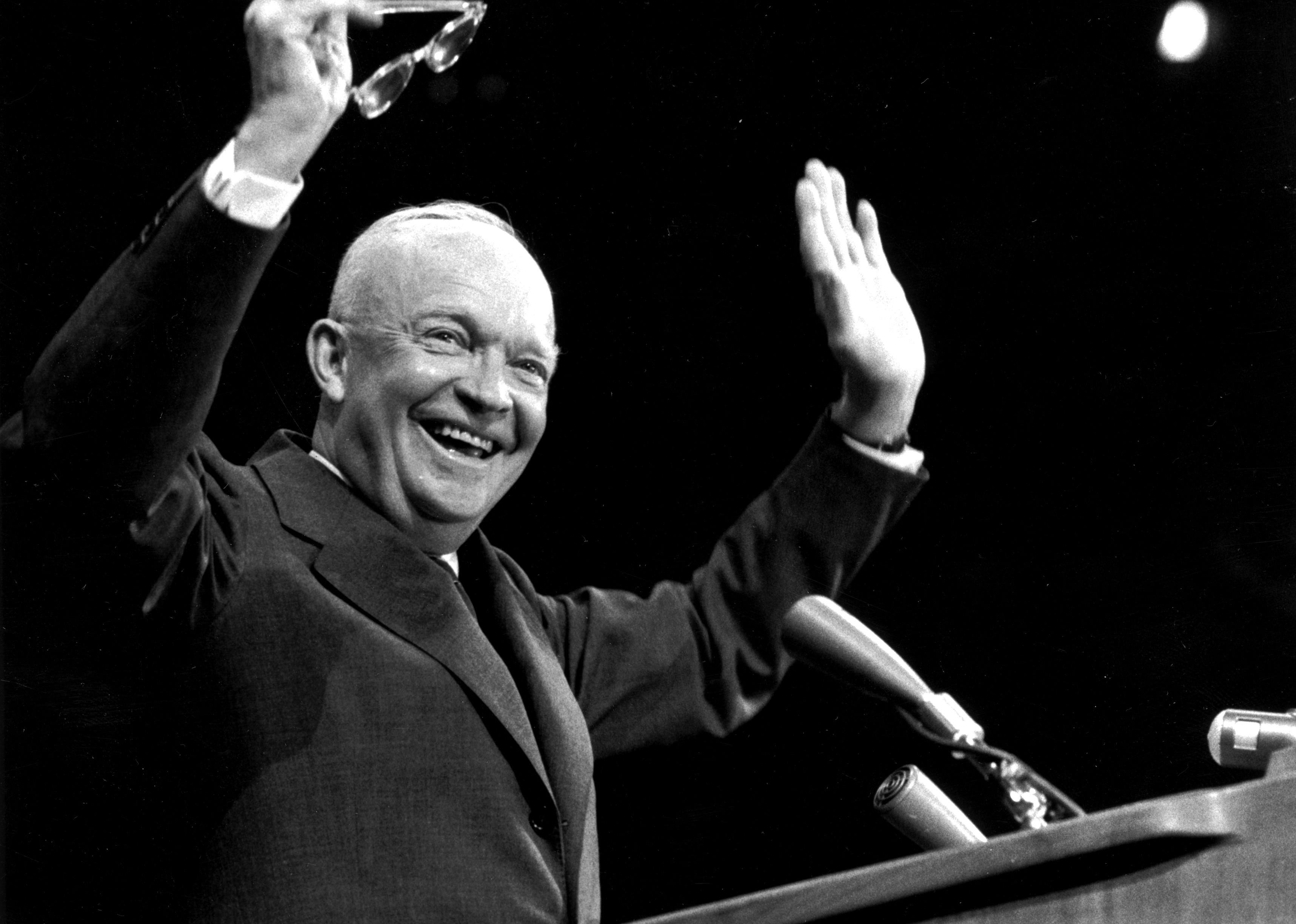 Dwight D. Eisenhower smiling and waving onstage.
