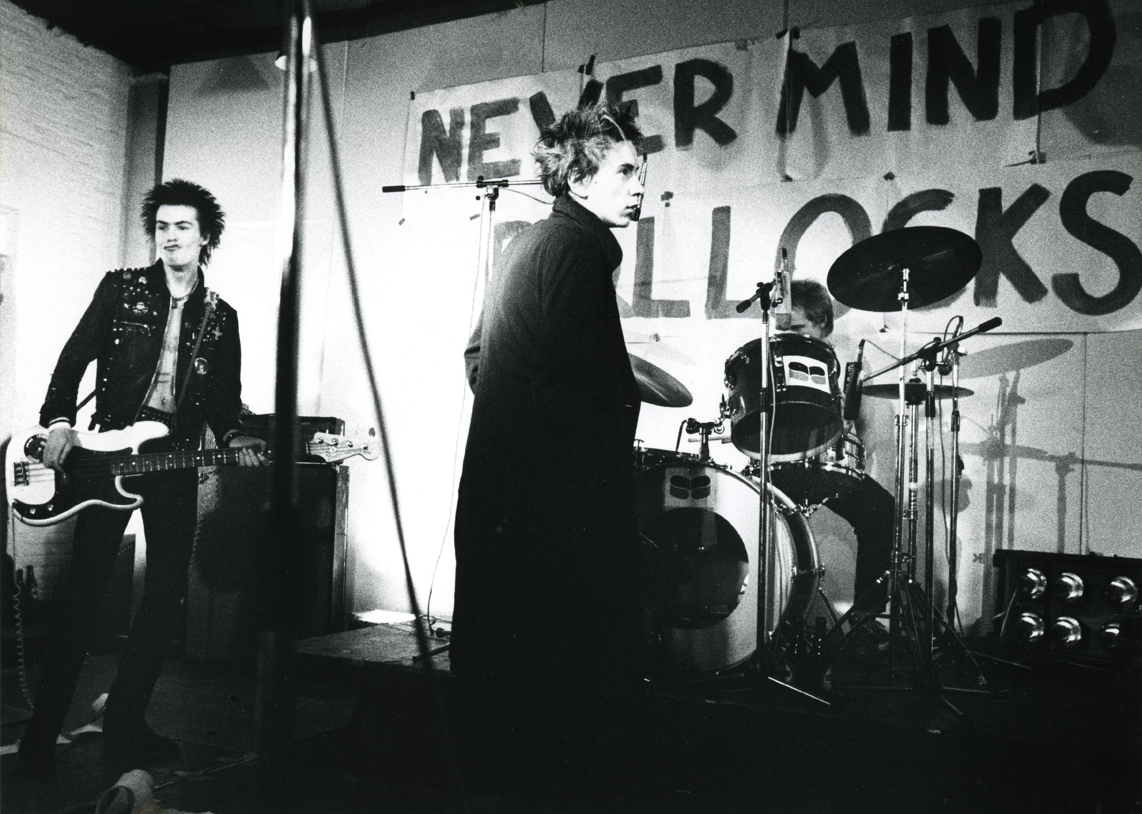 The Sex Pistols perforing onstage in all black.