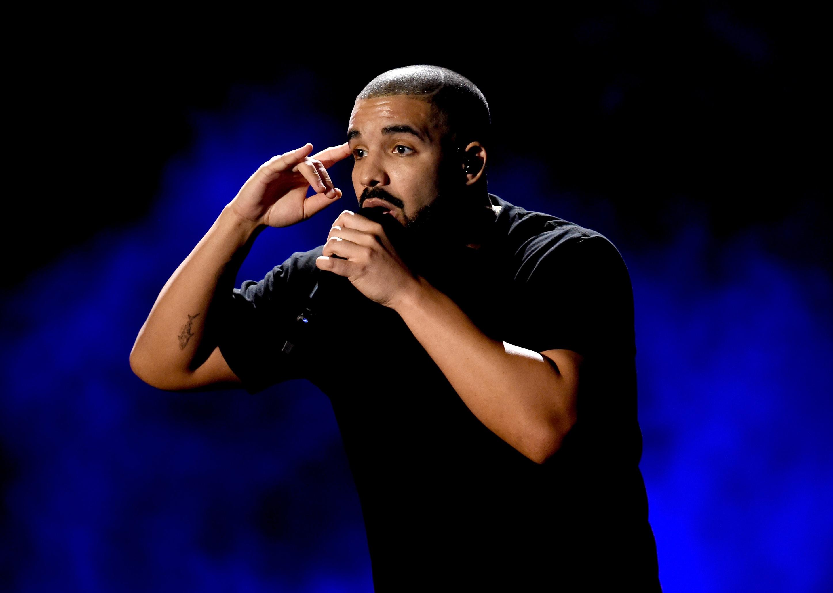 Drake onstage against a blue backlight.