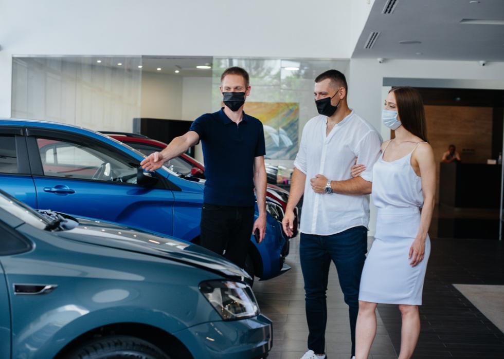 People in masks looking at cars.
