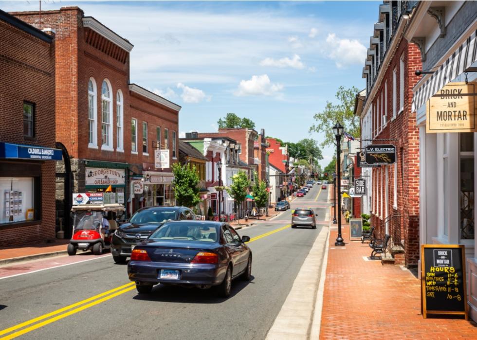 Cars driving down small street lined with brick buildings in Leesburg, Virginia.