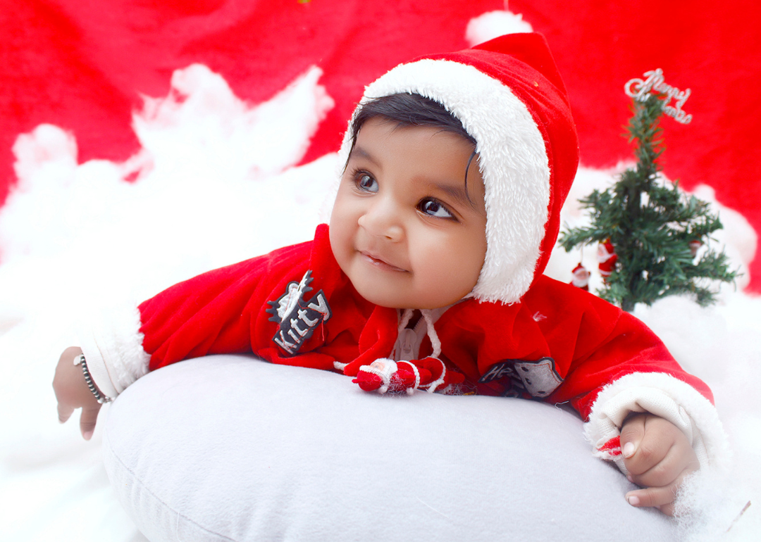 A baby girl in a red santa suit and hat.