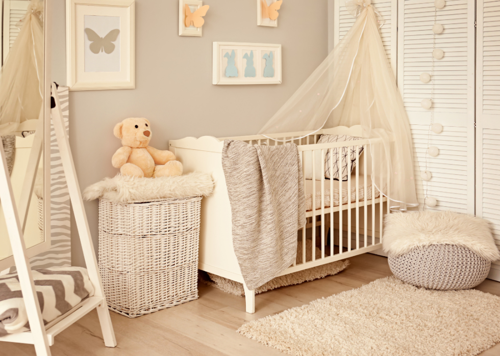 A nursery in beige tones with butterflies on the wall above the crib.