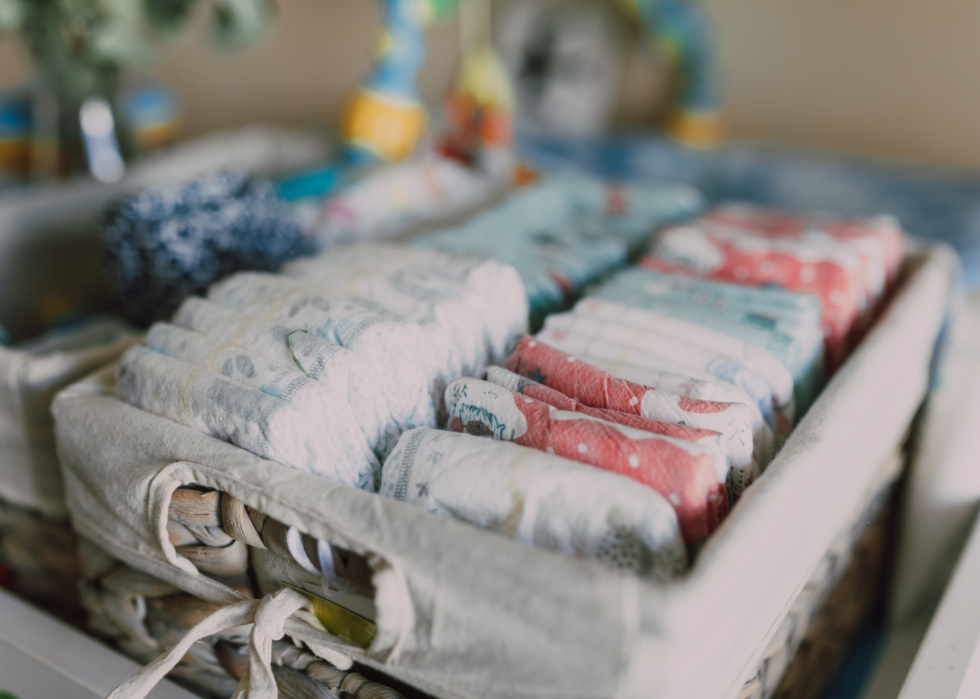 Diapers lined up in a woven basket.