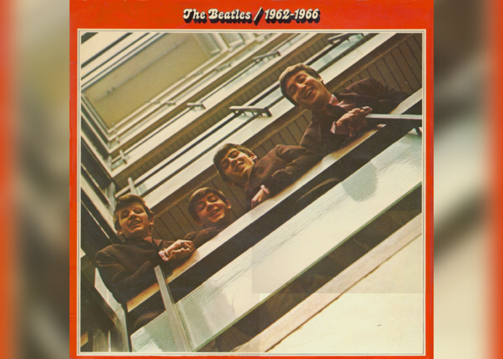The Beatles looking down from a railing and smiling.