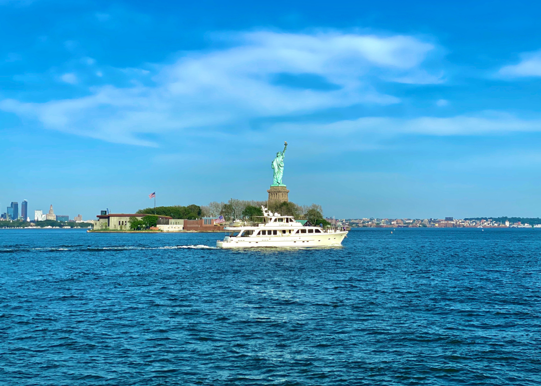 A boat on the water with the statue of liberty in the background.