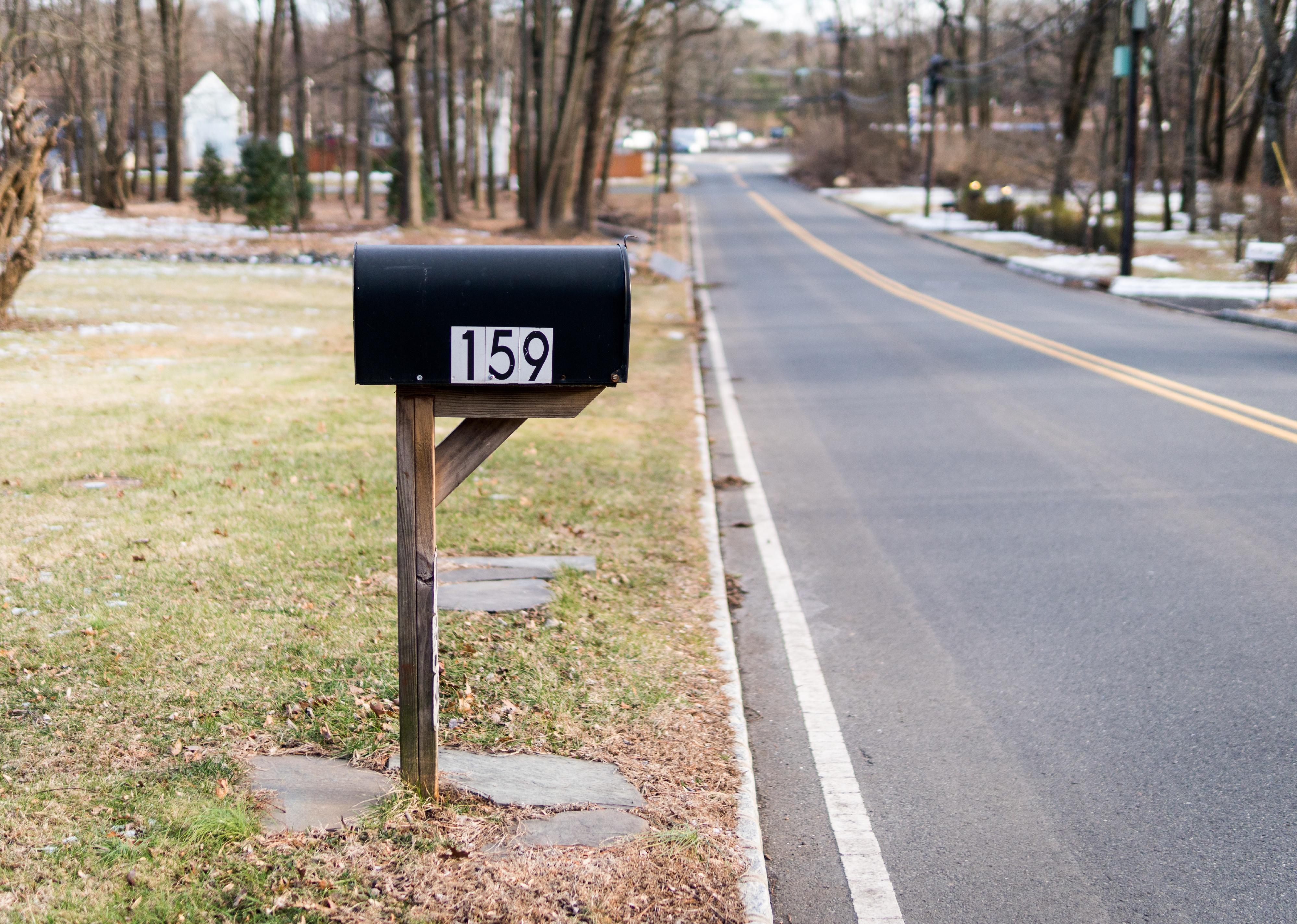 A black mailbox on a residential street.