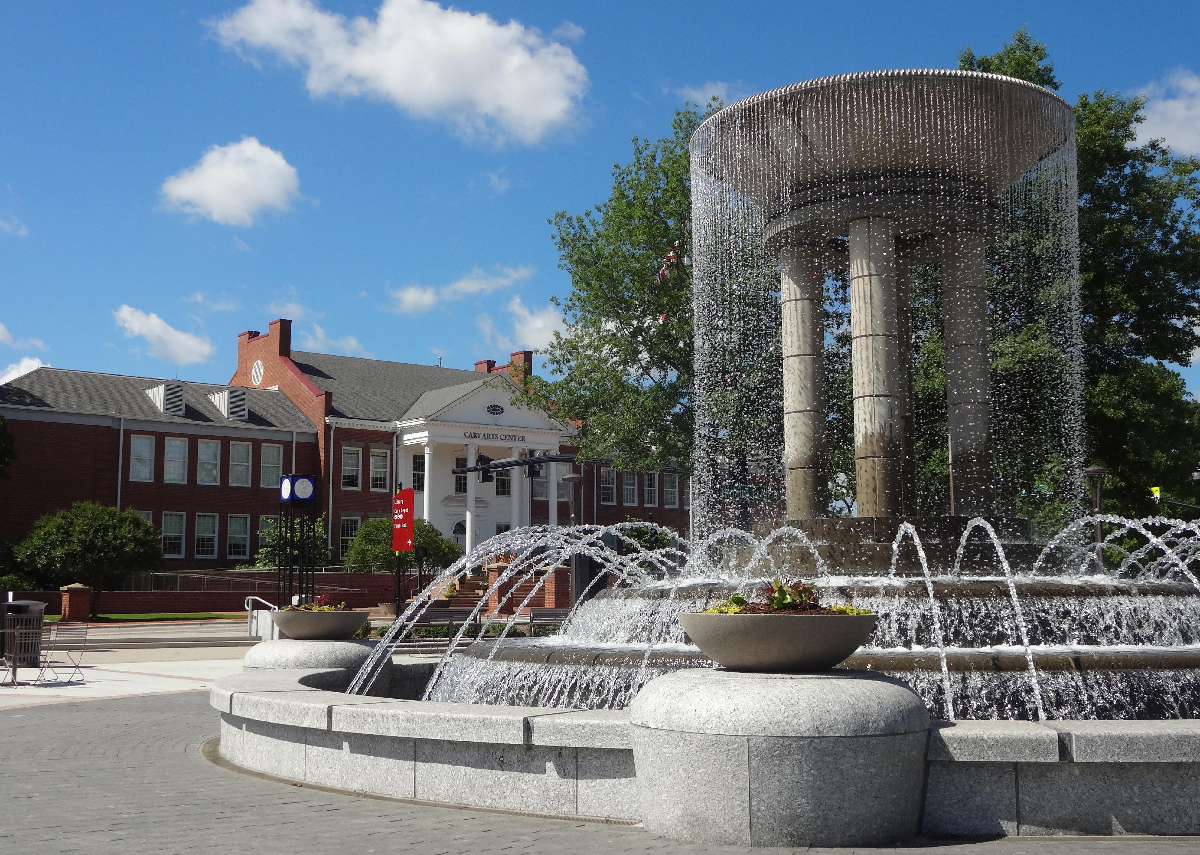 A large water fountain in front of a brick building with white columns.