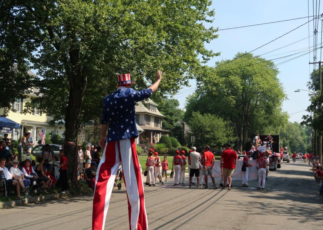 A 4th of July parade with a man in stilts dressed as uncle Sam.