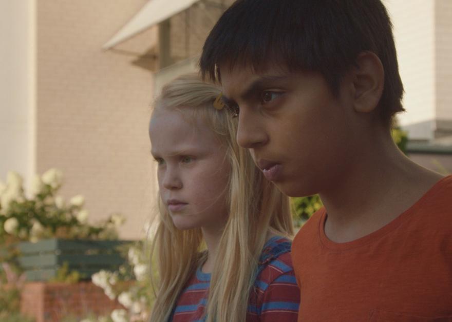 A young boy and girl looking at something outside with serious looks on their faces