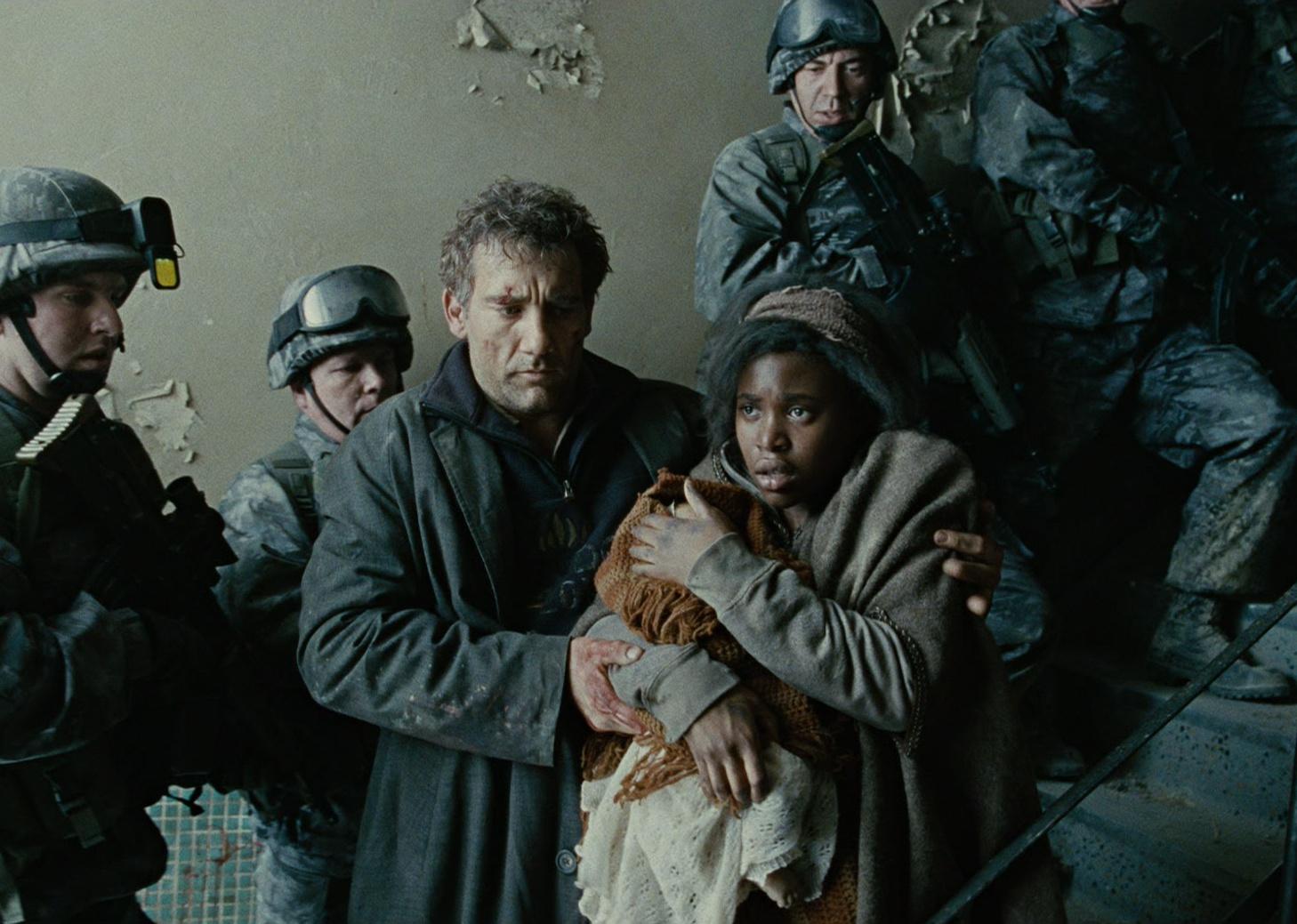 Clive Owen stands at the bottom of a flight of stairs protecting a young woman holding a baby with military men lining the stairs.