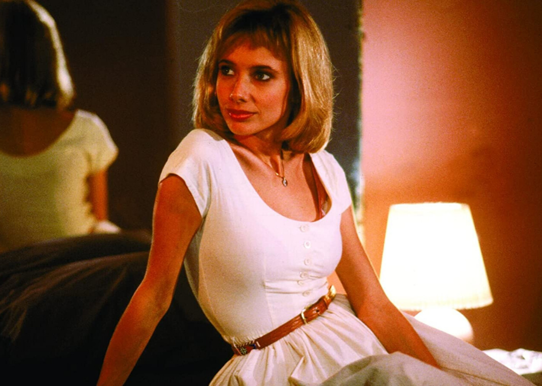 Rosanna Arquette in a white fitted dress with a thin brown belt.