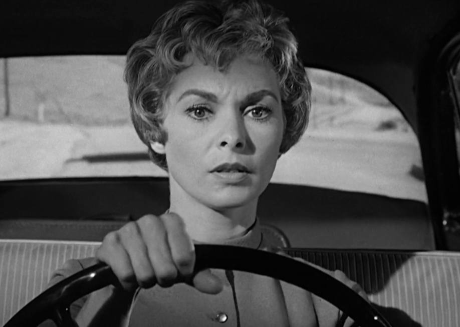 A woman driving and looking scared.